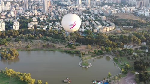 Aerial Shot Of Hot Air Balloon Descending Over Yarkon Park Against Sky In City