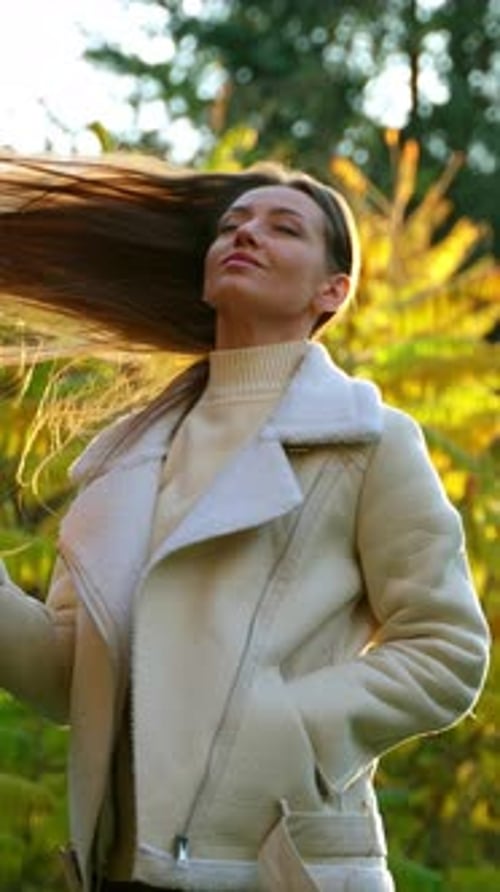 Beautiful young woman waving her long gorgeous dark hair in the rays of sun.