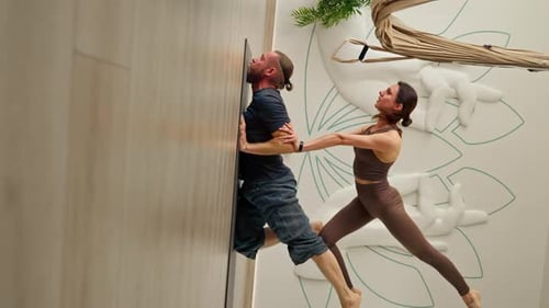 vertical video couple man and woman doing yoga exercises together lying on the floor in the gym