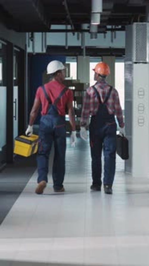 Construction Workers Walking Through a Contemporary Office Space Filled with Activity