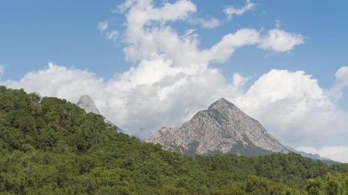 Timelapse of a Bright Sunny Day in the Mountains and Forested Hills With Drifting Clouds Receding