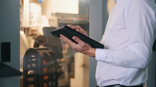 Digital tablet in hands. Close up view of man that is working in the modern factory.