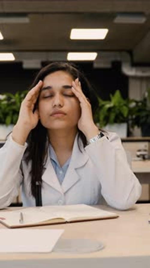 Stressed Female Doctor Suffering From Headache at Work