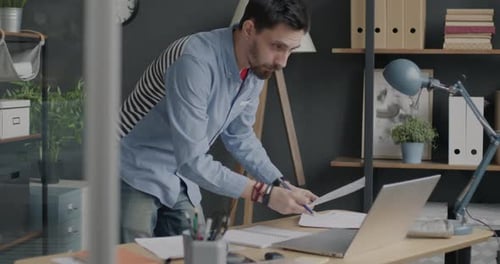 Portrait of Businessman Working with Documents and Using Laptop Concentrated on Paperwork in Office