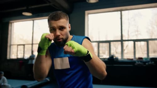 Close-up portrait of a boxer boy with elastic bandages on his hands fighting a shadow