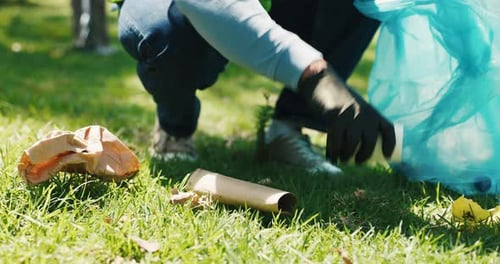 Person Collecting Trash on Grass in an Urban Park