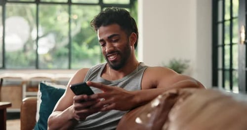 Man Relaxing on Couch While Using Smartphone