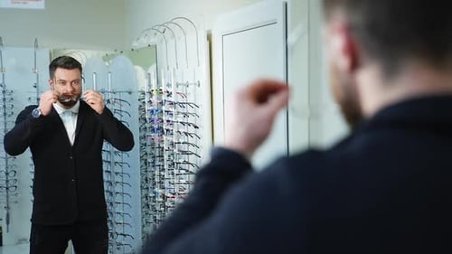 Portrait of fashion model man in modern casual outfit holds sunglasses standing in optics.