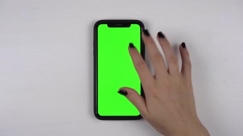 A Woman Uses a Smartphone Lying on the Table