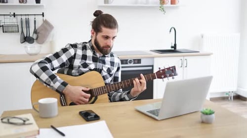 Personne caucasienne tenant un instrument à cordes tout en souriant à la webcam de l'ordinateur