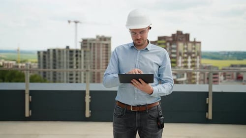 Construction Engineer Using Tablet for Project Management on Rooftop Site
