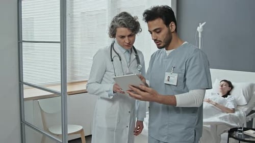 Doctor and Nurse Consulting Tablet in Hospital Room