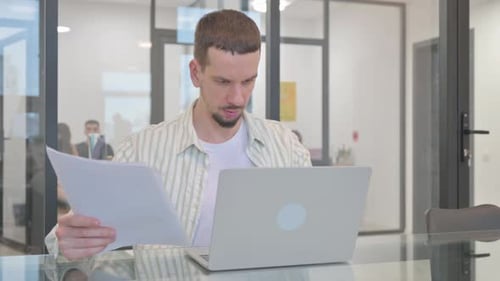 Man Receives Good News Working at Laptop in Office