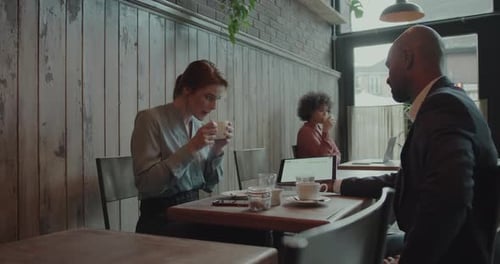 Coworkers having a Meeting in a Cafe using Digital tablet