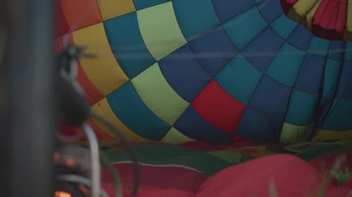 Woman Grips Hot Air Balloon Near Burner Flame in Grassy Field Preflight