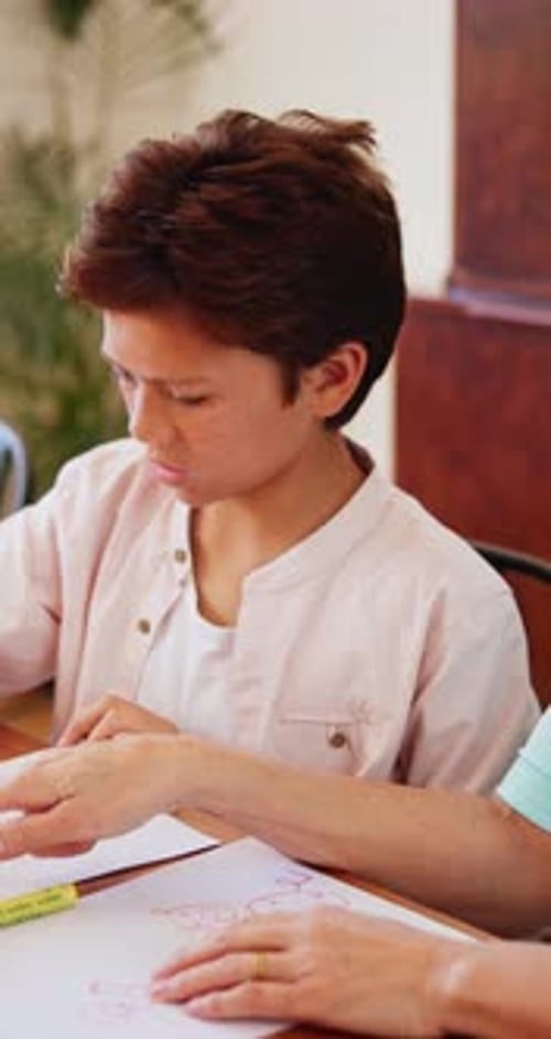 Child Drawing with Adult at Table Indoors