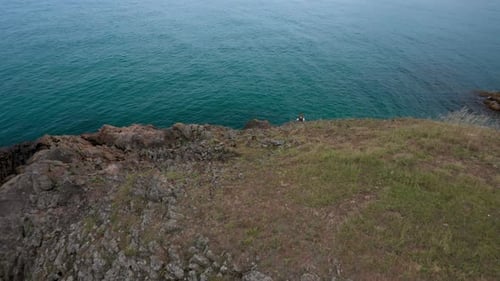 Woman at a scenic rocky shore surrounded by turquoise sea waters