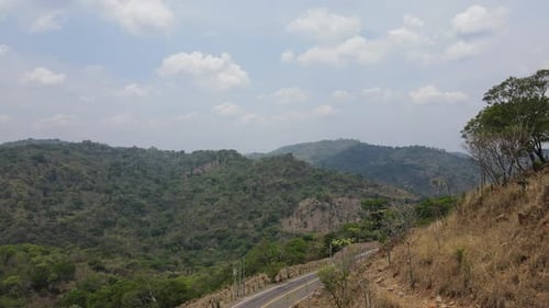 Aerial view in the foreground of a road with extreme curves and mountains in the background under a