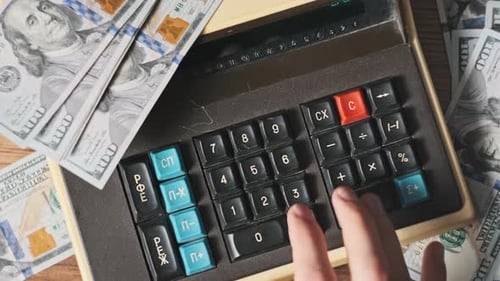Top View Counting on Old Vintage Calculator Surrounded By Dollar Bills CloseUp