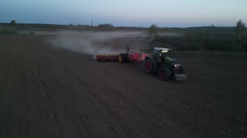 Green tractor works on the field sowing sunflower. Tractor planting corn in Ukraine