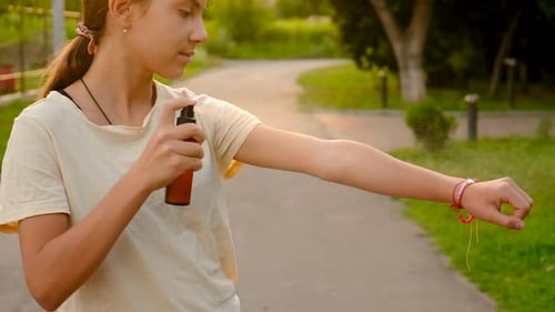 Teen Sprays Bug Repellent on Arm in Park