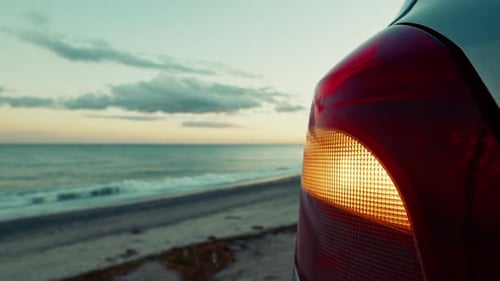 Car Parked on Beach at Sunset with Blinking Light