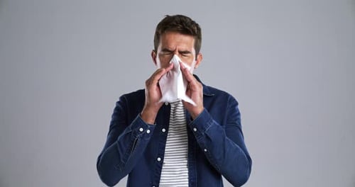 Man Blowing Nose into Tissue
