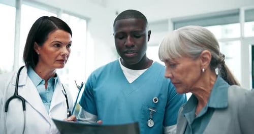 Medical Staff Discussing X-Ray With Senior Patient