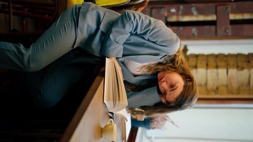 Vertical Video Close Up in Bookstore Near Window a Beautiful Student Sitting Boring Reading Books