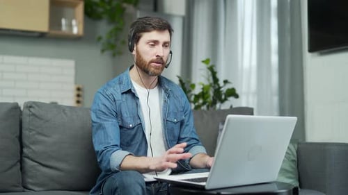 Ein Mann mit Kopfhörern, der einen Laptop benutzt, kommuniziert per Videochat. Männchen winkende Hände beim