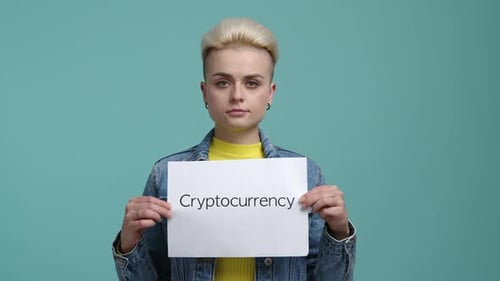 Femme caucasienne en vêtements décontractés tenant un livre blanc avec un mot cryptomonnaie