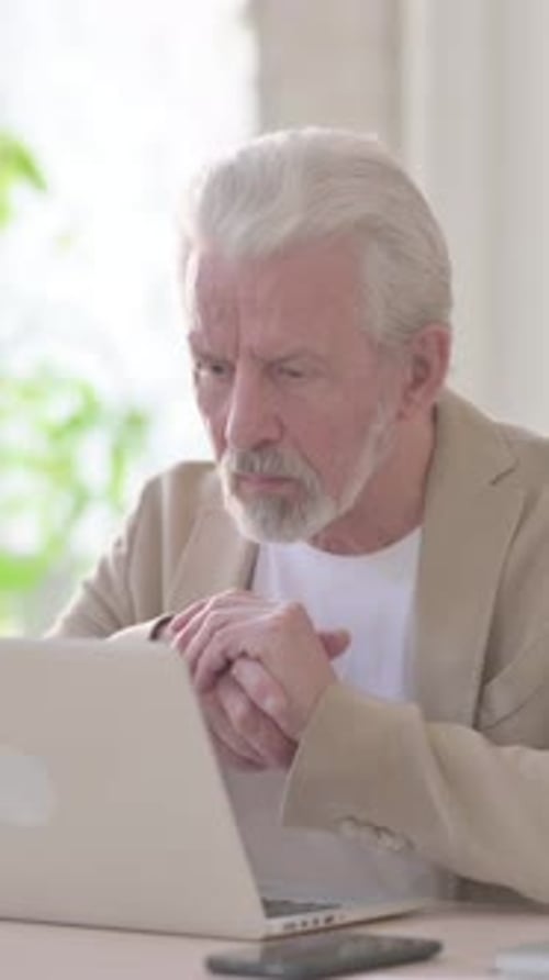 Old Man Thinking while Working on Laptop in Office, Vertical Video