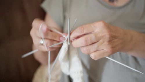 A Closeup of Two Hands Skillfully Knitting with Multiple Colorful Needles and Soft Yarn in a Cozy