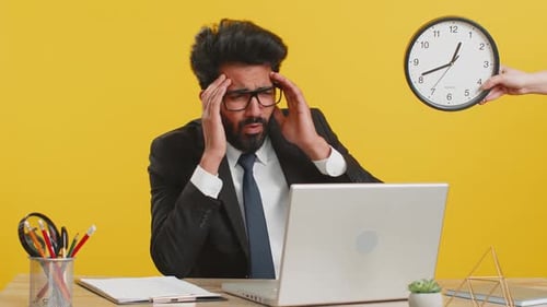 Indischer Geschäftsmann mit Angst, die Uhrzeit auf der Uhr zu überprüfen, zu spät zur Arbeit zu kommen, weil er sich verspätet hat, Frist