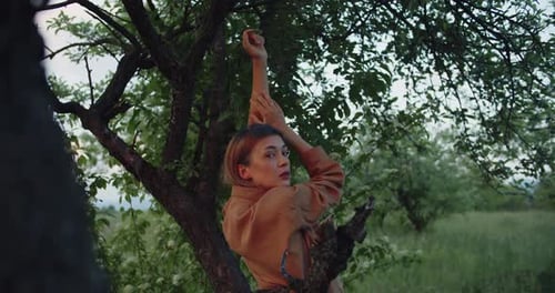 Beautiful female blonde model posing on a meadow in apple garden