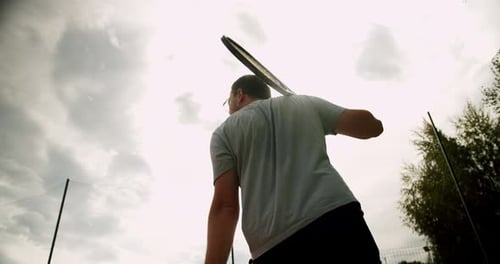 Tennis Player Swinging Racket on Cloudy Day