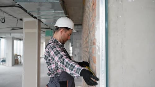 Construction Worker Measuring Brick Wall with Measuring Tape