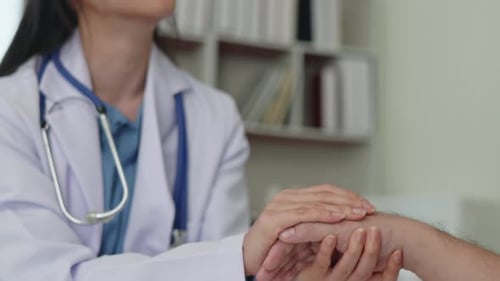 Doctor Examines Patient's Hand in Hospital Room