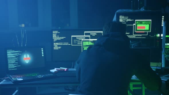 Moody Hacker Working Late Into the Night with Dual Monitors in a Dark ...