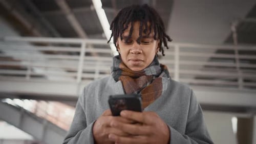 Portrait of Joyful Black Man with Smartphone Under Bridge Chatting Online Townsman in Urban