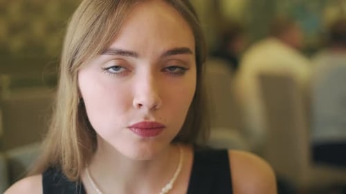 close-up shot of beautiful young woman eating her meal in restaurant. slow motion. 4K.. looking at c