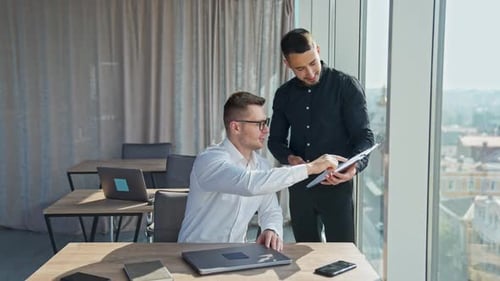 Mid-aged young office workers looking attentively at the documents discussing them.
