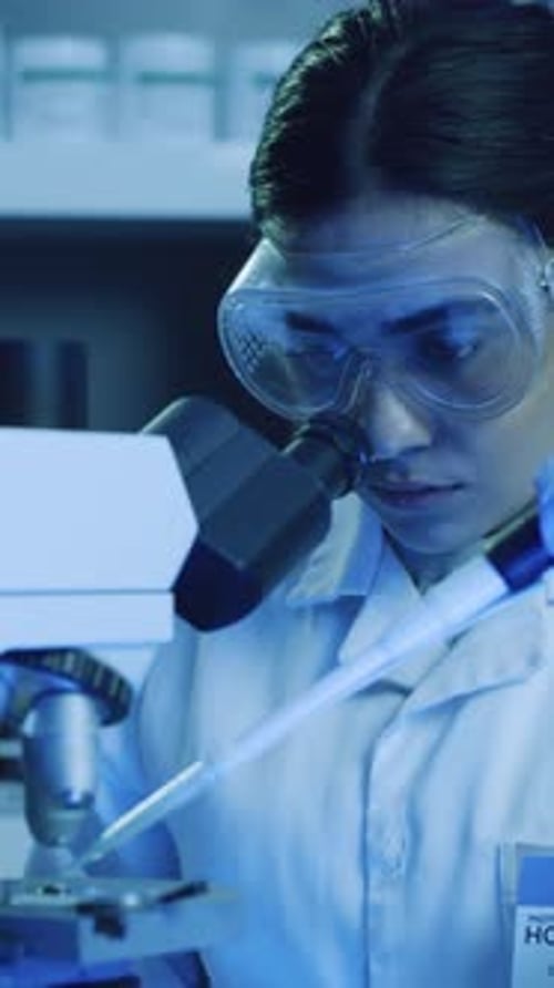Woman Lab Technician Inspects Sample with Microscope