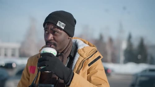 Press Photographer Sipping Coffee While Holding Camera in Snowy City