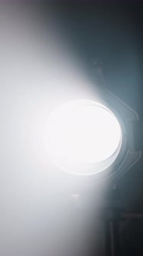 Projecteur de studio projetant un faisceau lumineux dans une pièce sombre et brumeuse