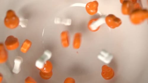Close up of orange skulls and bones shaped candy falling on a plate.