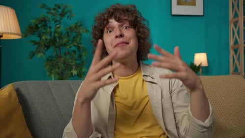 Young Man Sitting on Couch Talking to Camera