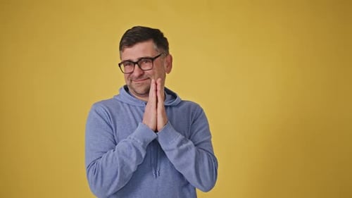 Homme senior plaidant avec des lunettes sur fond jaune