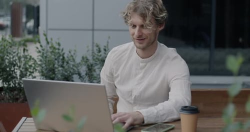 Joyful Male Freelancer Speaking Showing Thumbsup Making Online Video Call with Laptop in Street Cafe