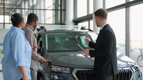 Salesman Presenting Car Features to Potential Buyers